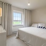 Minimalist bedroom with large white bed and lamp.