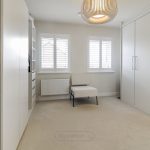 Modern minimalist bedroom with white wardrobe and chair.