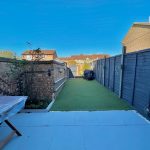 Back garden with artificial grass and brick walls.
