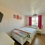 Cosy bedroom with double bed, TV, and window view.