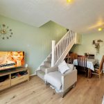 Living room with TV, dining area, and staircase.