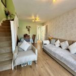 Cosy living room with sofa, dining table, and stairs.