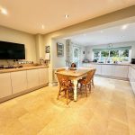 Modern kitchen and dining area with wooden table.