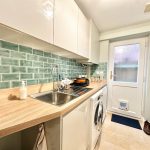 Modern kitchen with teal backsplash and wooden countertops.