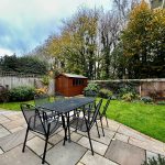 Garden with patio, table, chairs, and shed.