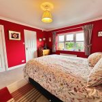 Cosy bedroom with red walls and floral bedding.