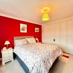 Bedroom with red walls and white wardrobe.