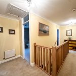 Carpeted hallway with wooden banister and artwork.