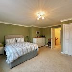 Spacious bedroom with green walls and double bed.