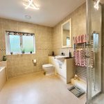Modern tiled bathroom with shower and bathtub.