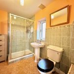 Modern bathroom with shower, sink, toilet, and mirror.