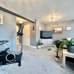 Modern living room with exercise bike and plants.