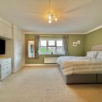 Spacious bedroom with double bed and TV.