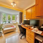 Cosy home office with desk, computer, and sofa.