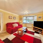 Cosy living room with red sofas and large TV.
