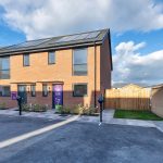 Modern brick house with solar panels and driveway.
