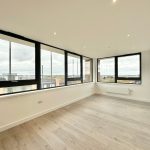 Modern empty room with large windows and wooden floor.