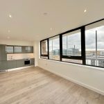 Modern flat with large windows and kitchen view.