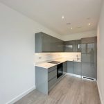 Modern kitchen with grey cabinets and wooden flooring.