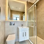 Modern bathroom with shower, sink, and toilet.