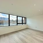 Bright modern room with large windows and wooden floor.