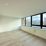 Spacious empty room with large windows and wooden floor.