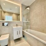 Modern bathroom with large mirror and tub.