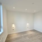 Minimalist empty room with wooden flooring and window.