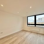 Empty room with wood flooring and large window.