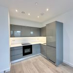 Modern kitchen with grey cabinets and wooden floor.