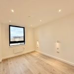 Empty room with wooden floor and large window.