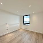 Empty bright room with wooden flooring and window view.