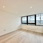 Bright empty room with large windows and wooden floor.