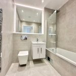 Modern bathroom with chrome fixtures and large mirror.