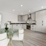 Modern kitchen with white cabinets and dining area.