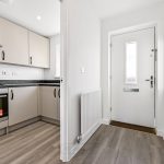 Modern kitchen with entrance door and wooden flooring.