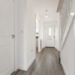 Modern hallway with wooden flooring and white walls.