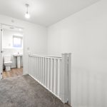 White hallway with bathroom view and grey carpet