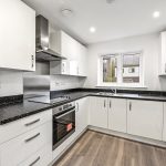 Modern kitchen with white cabinets and black countertops.