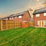 Back garden with wooden shed and brick house.