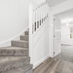 Modern white interior with carpeted stairs and doorway.