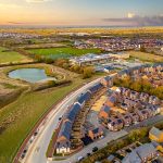 Aerial view of suburban houses and fields at sunset.