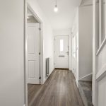 Modern hallway with wooden floor and white walls.