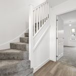 Modern hallway with carpeted stairs and open door.