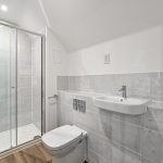 Modern bathroom with shower, sink, and toilet.