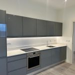 Modern kitchen with grey cabinets and built-in oven.