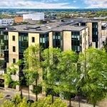 Modern office building with trees and car park.
