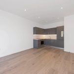 Modern kitchen with wooden flooring and grey cabinets.