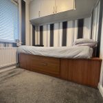 Single bed with striped wallpaper in bedroom.
