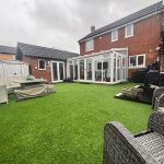 Modern patio with artificial grass and outdoor seating.